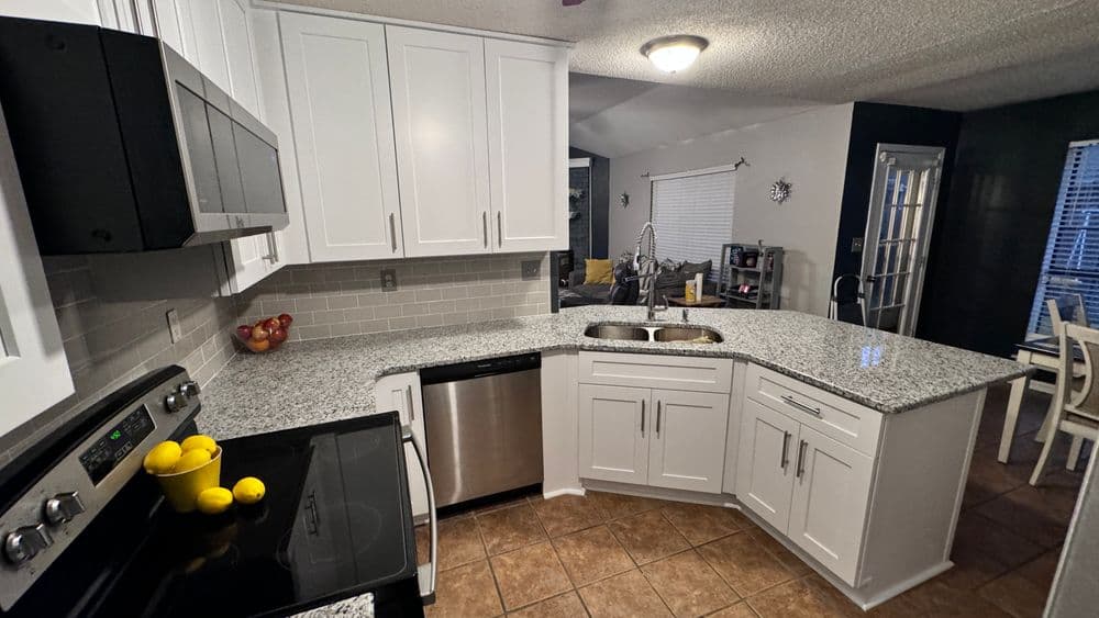 Modern kitchen with white cabinets, granite countertops, and stainless steel appliances.
