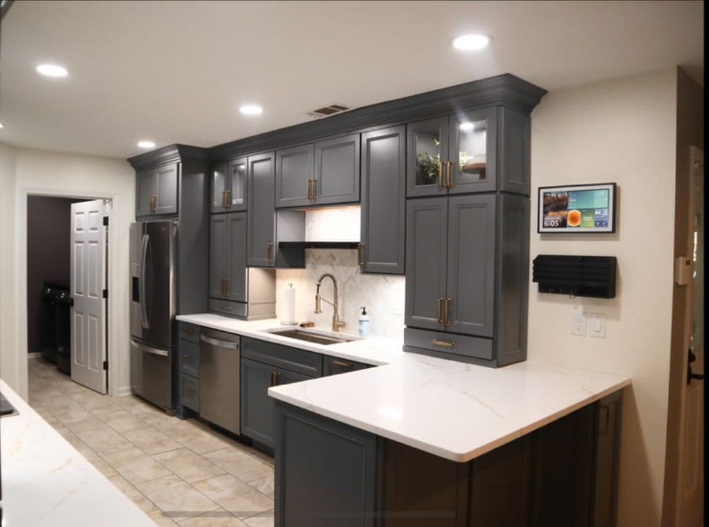 Modern kitchen with gray cabinets, white marble countertops, and stainless steel appliances.