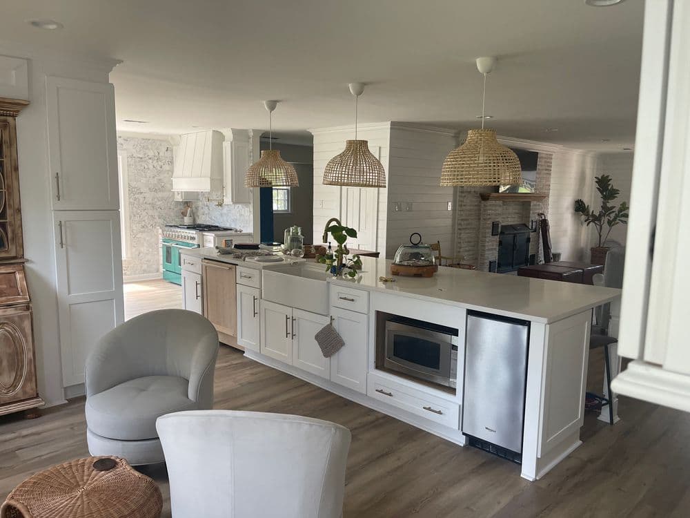 Modern kitchen with white cabinetry, island, stainless steel appliances, and woven pendant lights.
