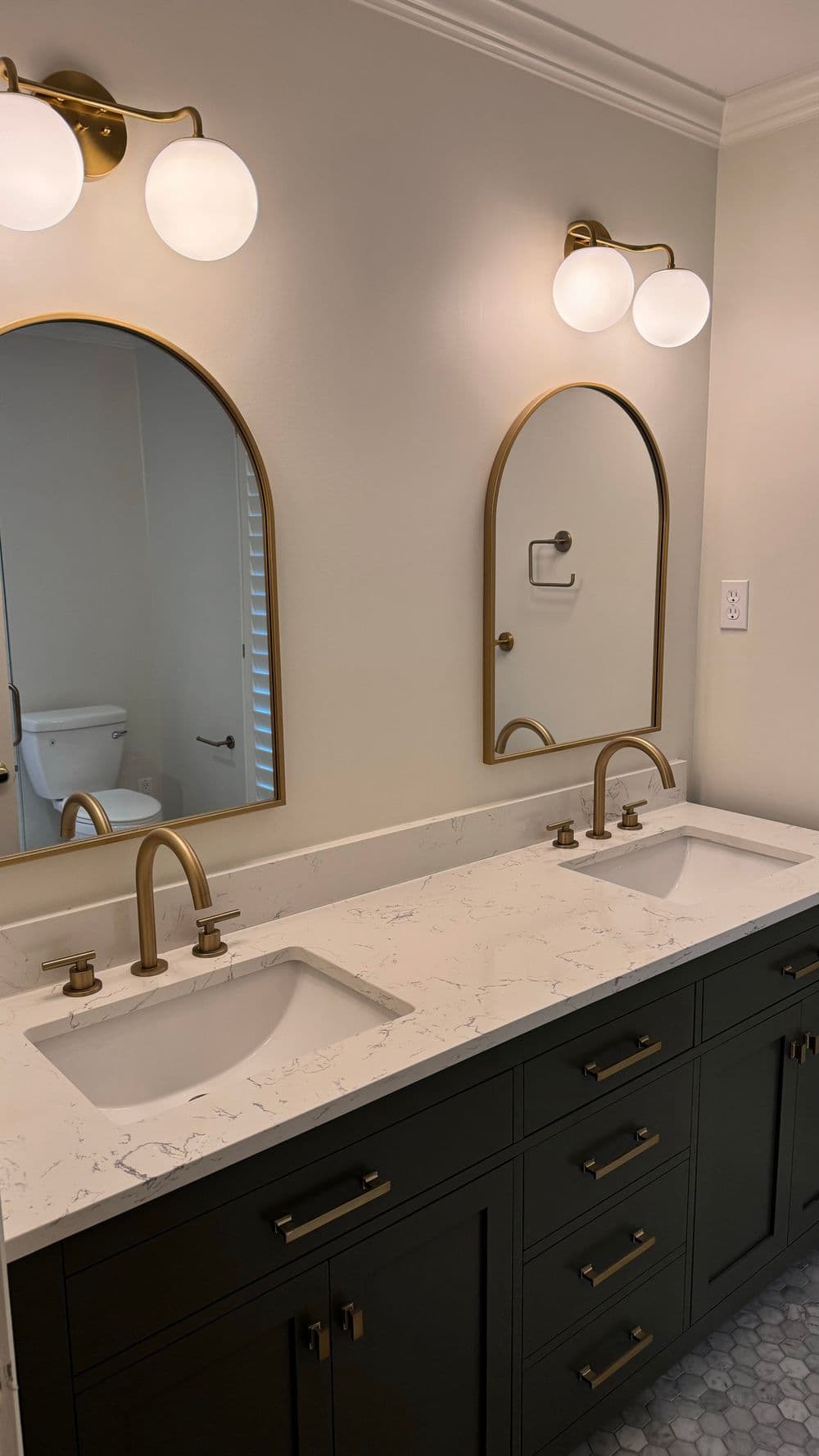 Modern bathroom with double sinks, marble countertop, and elegant brass fixtures.