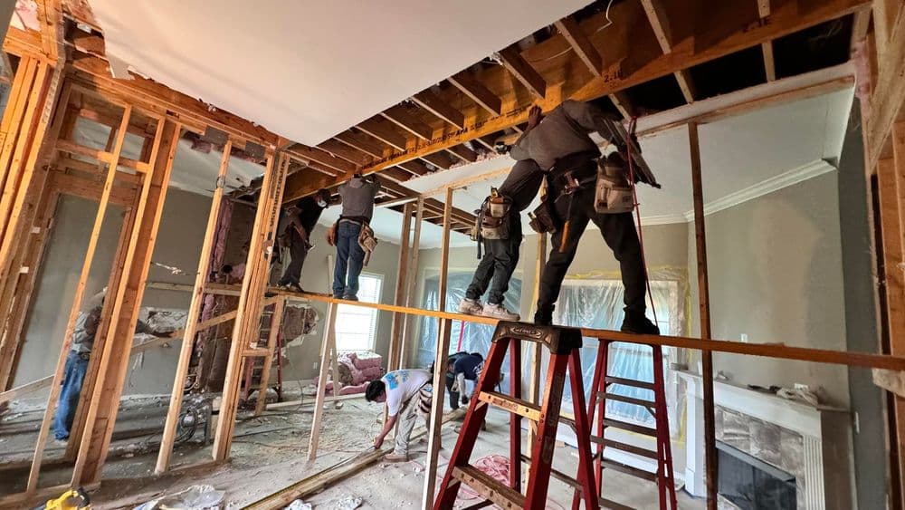 Construction workers renovating a living room, installing ceiling beams and drywall.