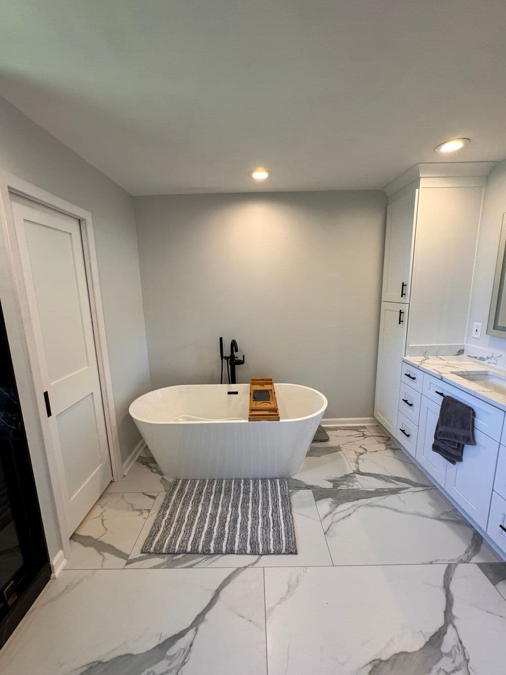 Modern bathroom featuring a freestanding tub, marble flooring, and sleek cabinetry.