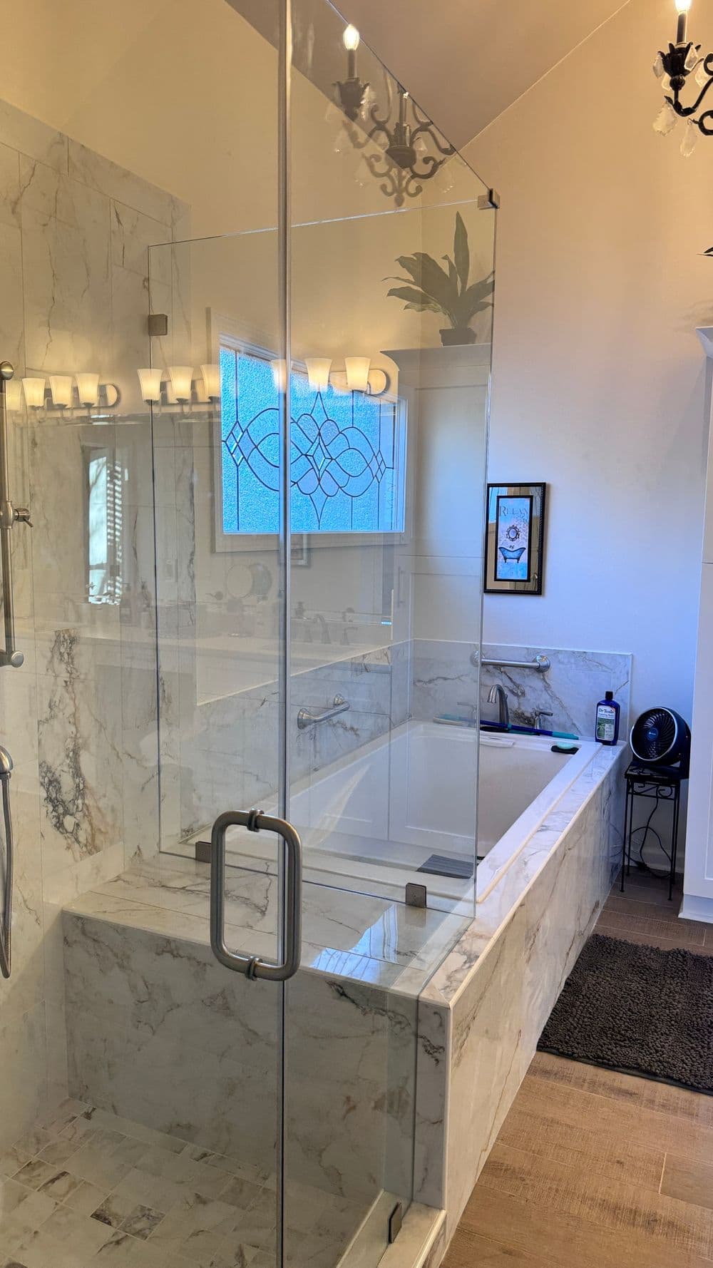 Modern bathroom featuring a glass shower, soaking tub, marble walls, and elegant lighting.