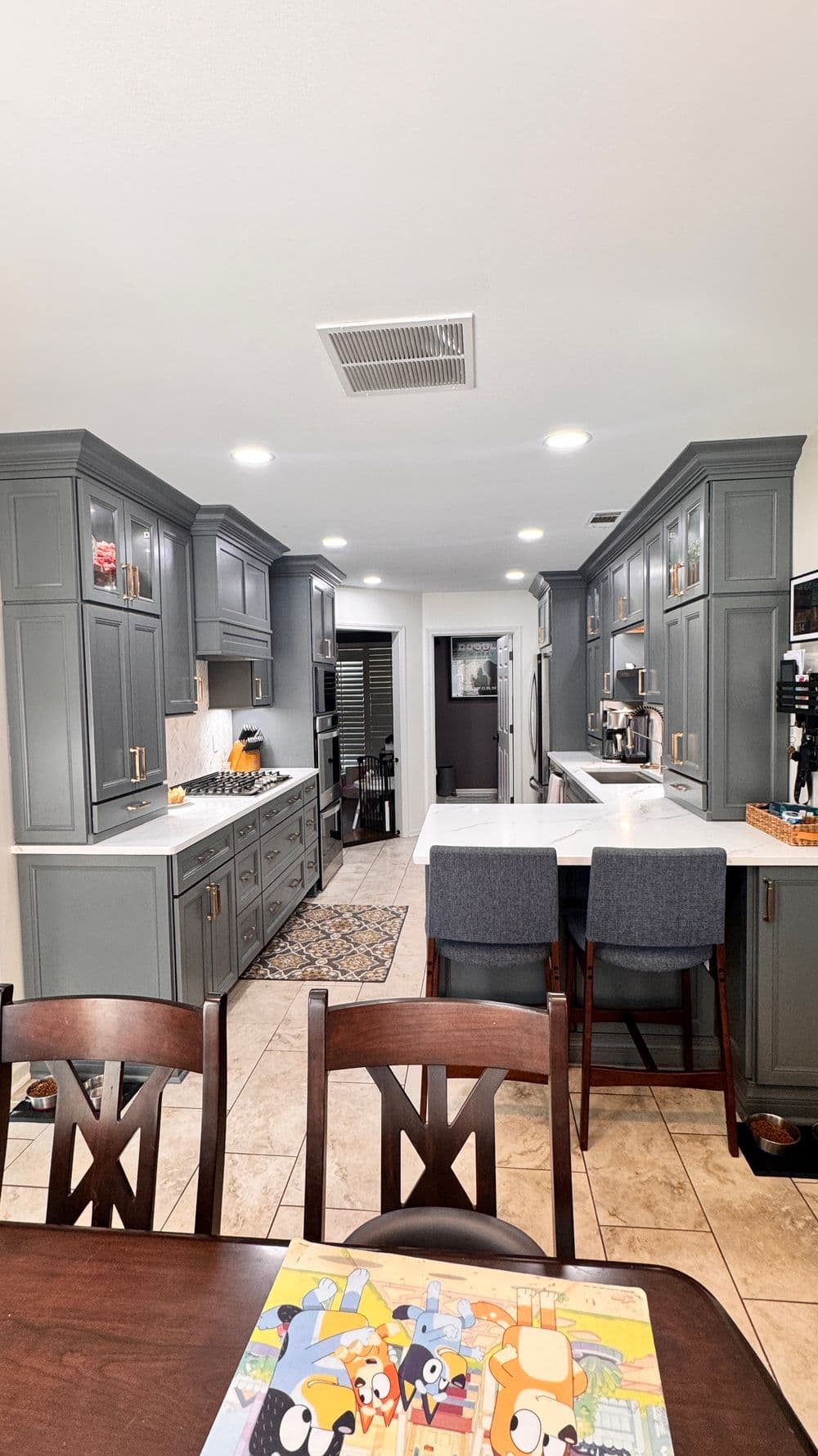 Modern gray kitchen with white countertops, stainless steel appliances, and a cozy dining area.