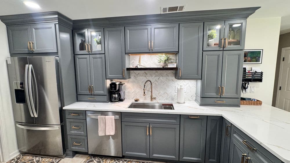Modern kitchen with gray cabinets, marble countertops, stainless steel appliances, and stylish decor.