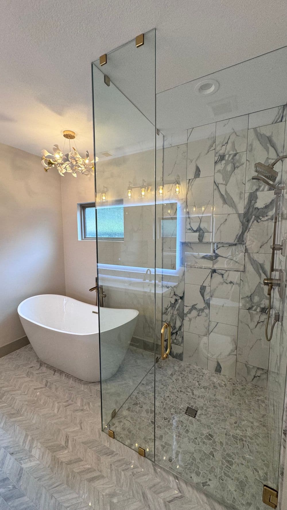 Modern bathroom with freestanding tub, glass shower, marble walls, and stylish lighting.