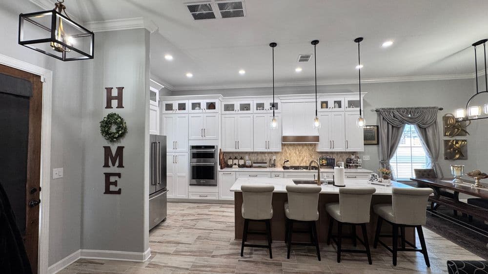 Modern kitchen with white cabinets, island seating, and stylish pendant lighting.