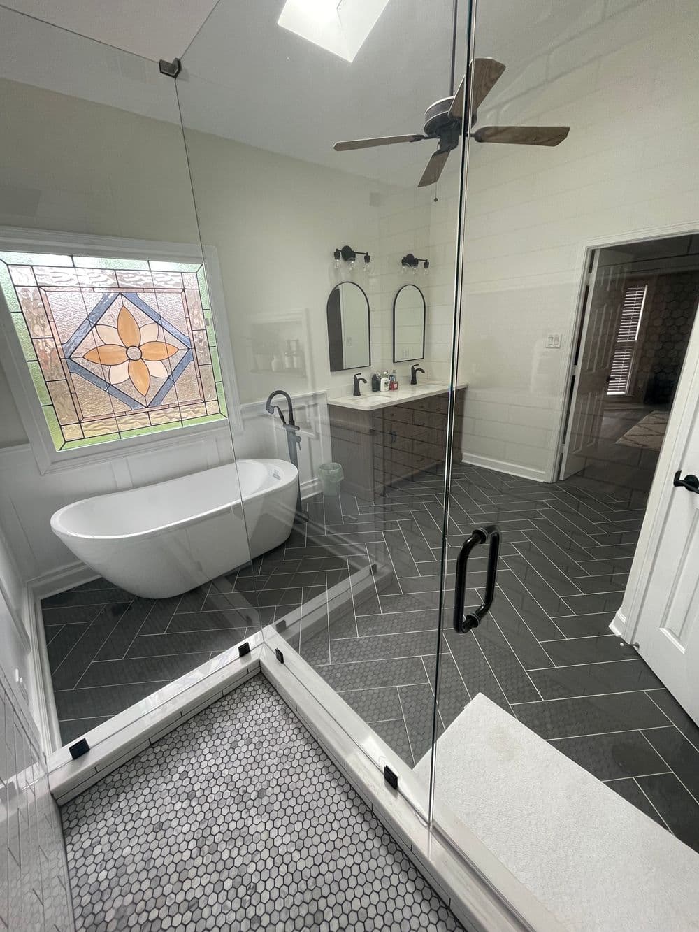 Modern bathroom with freestanding tub, double sinks, and stylish herringbone tile flooring.