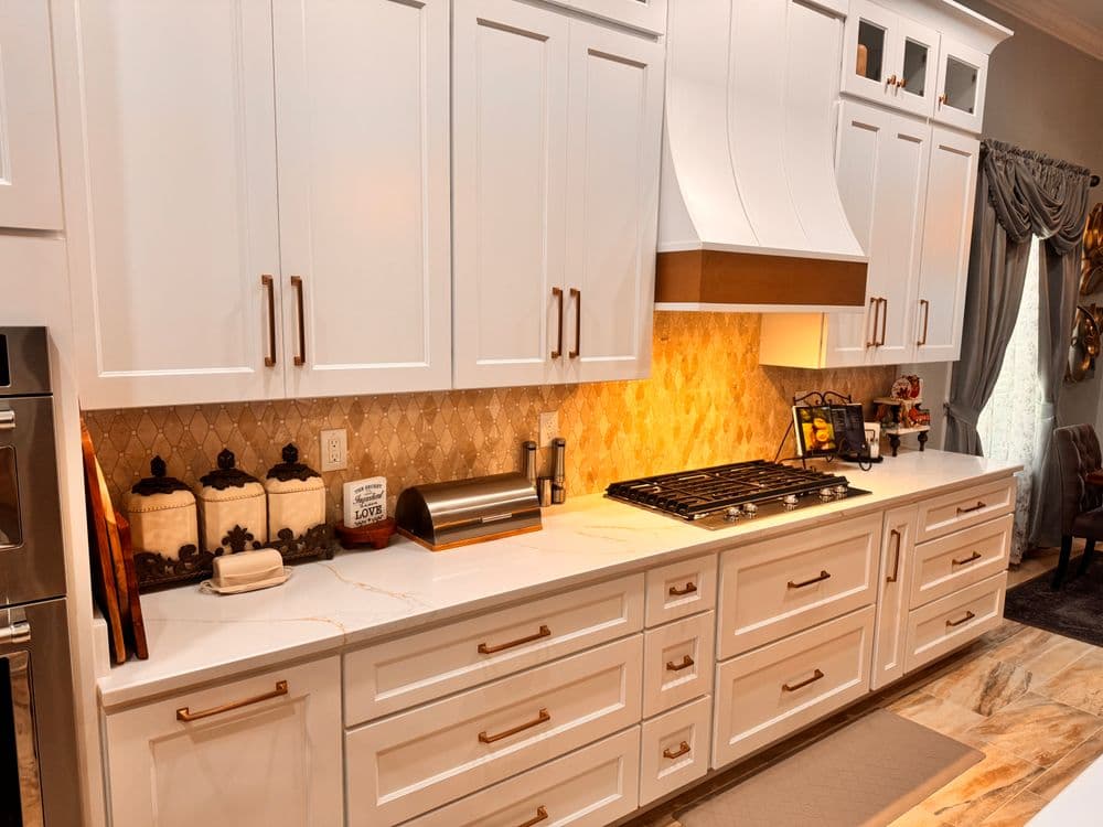 Modern kitchen with white cabinets, quartz countertop, and elegant backsplash design.