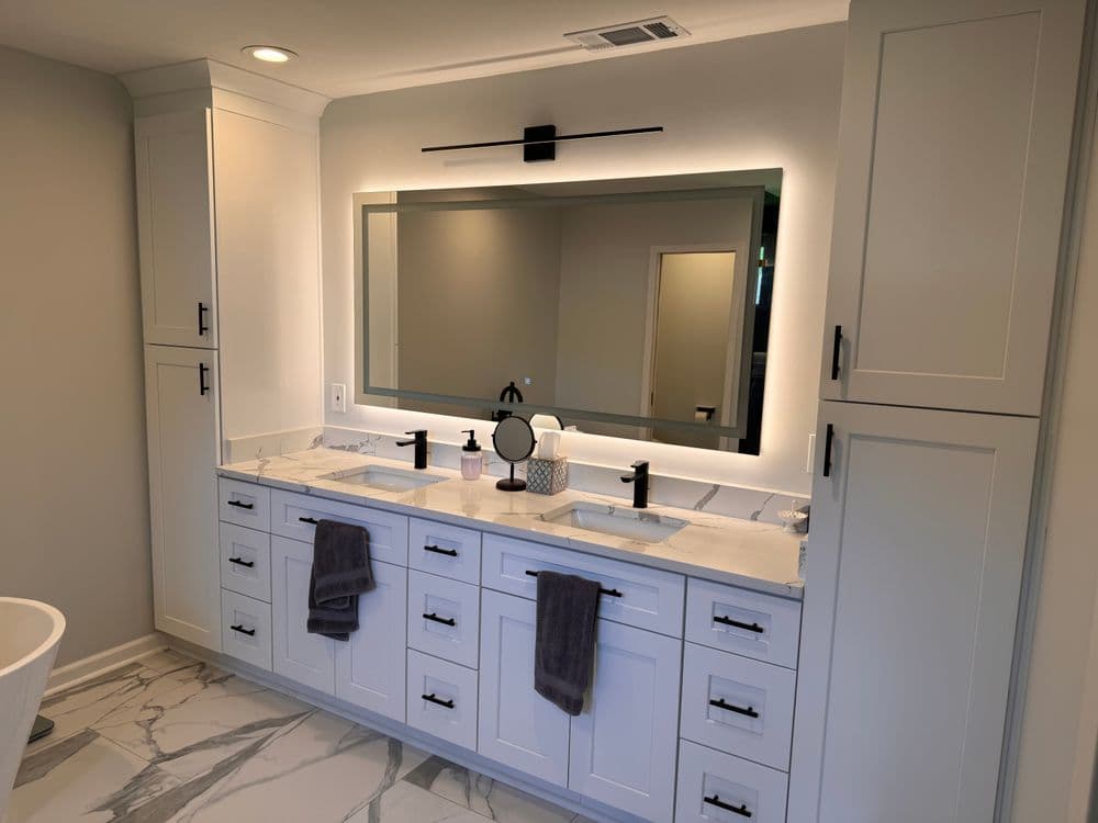 Modern bathroom with double sinks, marble countertop, large mirror, and stylish cabinetry.