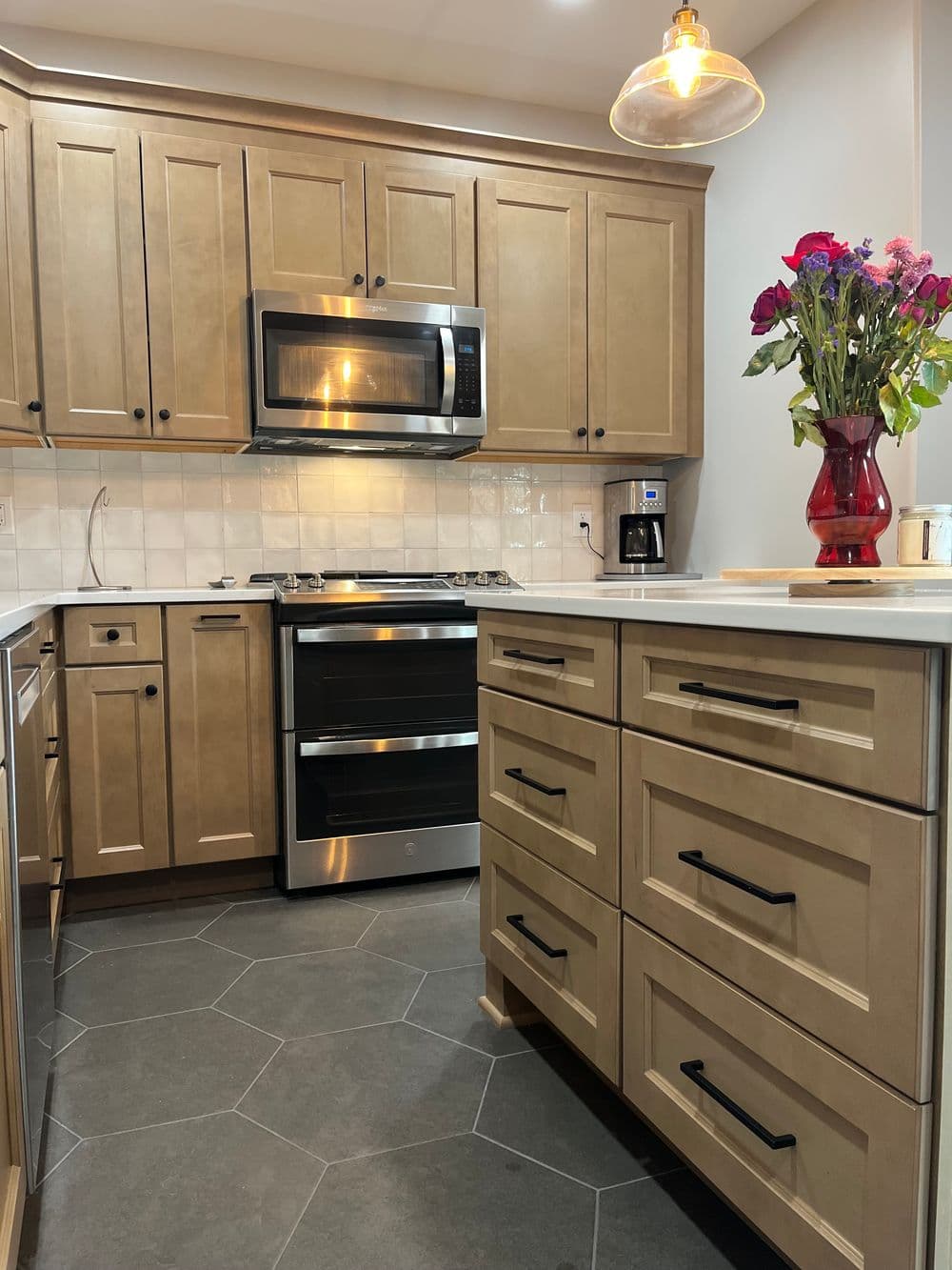 Modern kitchen with stainless steel appliances, wooden cabinets, and a vase of flowers.