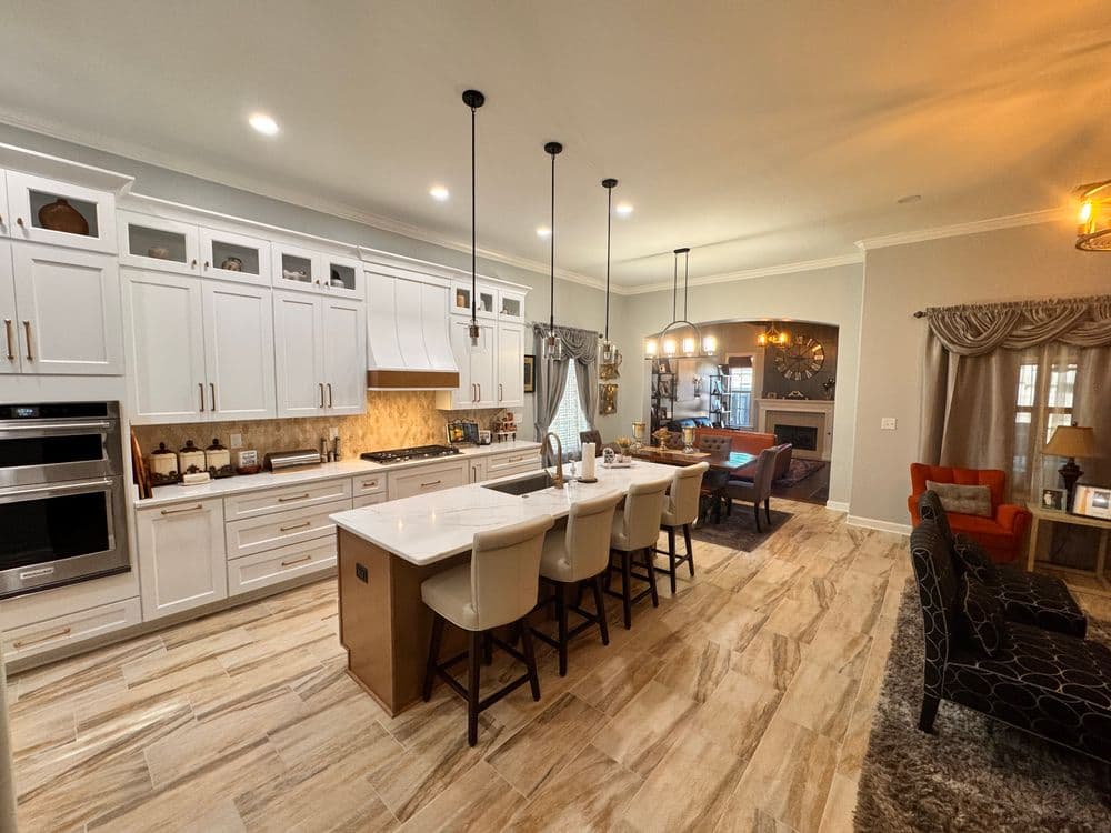 Modern kitchen with white cabinetry, island seating, and open living space design.