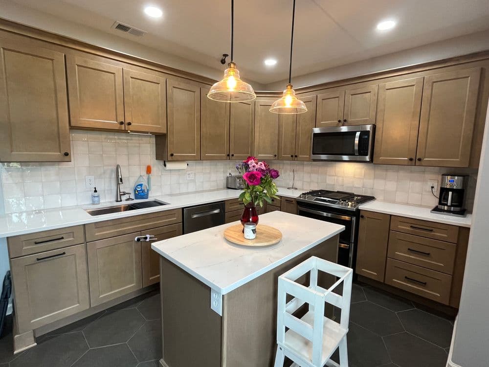 Modern kitchen with wooden cabinets, stainless steel appliances, and a floral centerpiece on an island.
