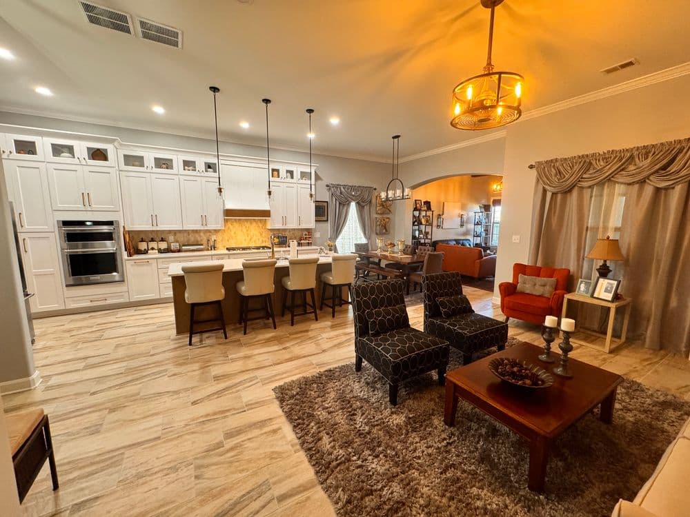 Modern open-concept kitchen and living room with elegant furniture and warm lighting.