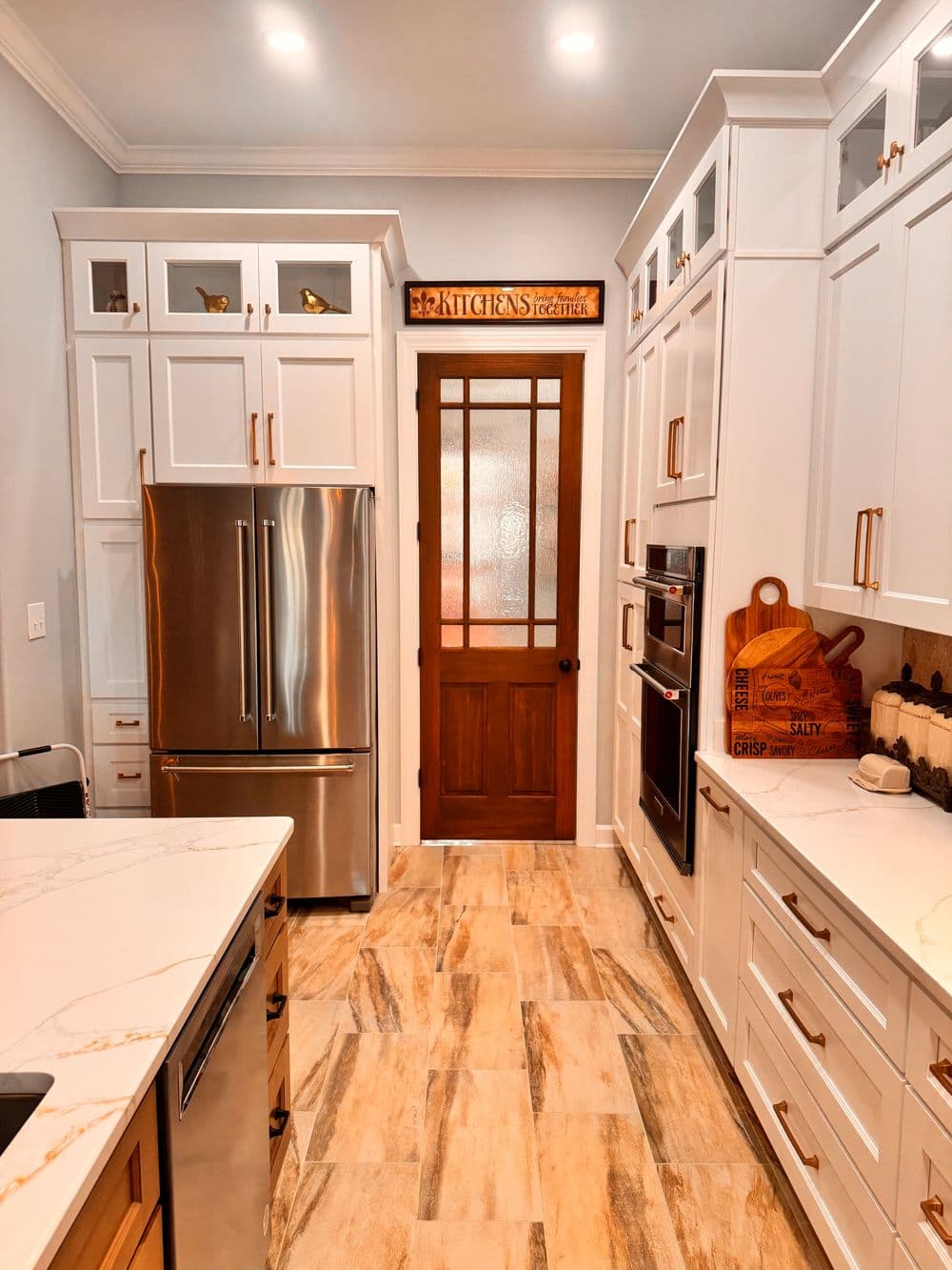 Modern kitchen with stainless steel appliances, white cabinetry, and a wooden door.
